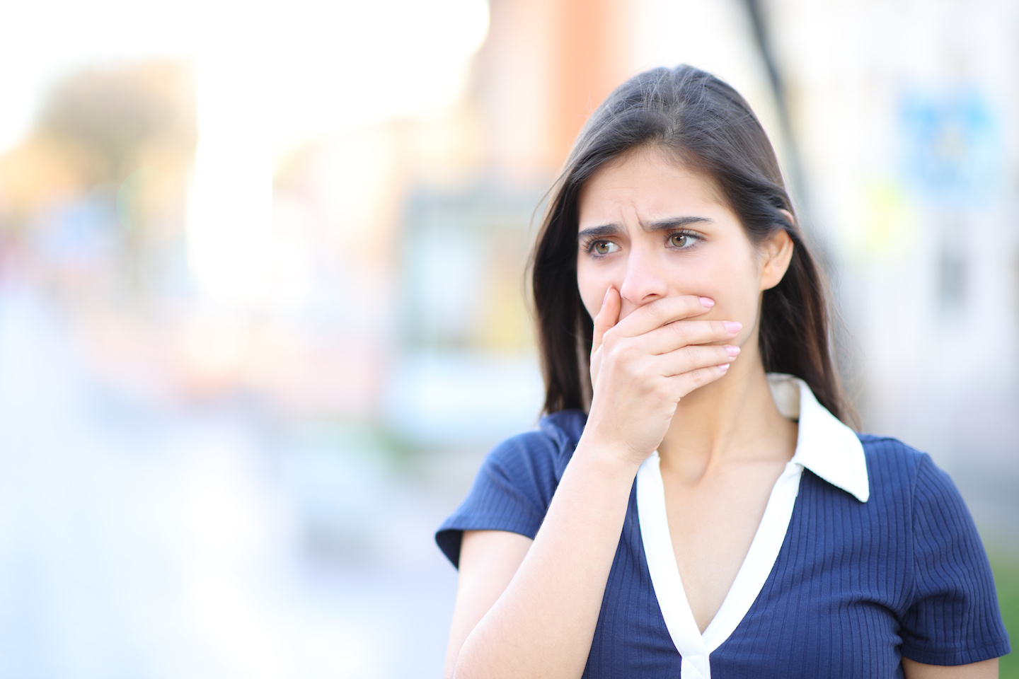 A woman with her hand covering her mouth, in shock, on the street. Depicts an eyewitness testimony.