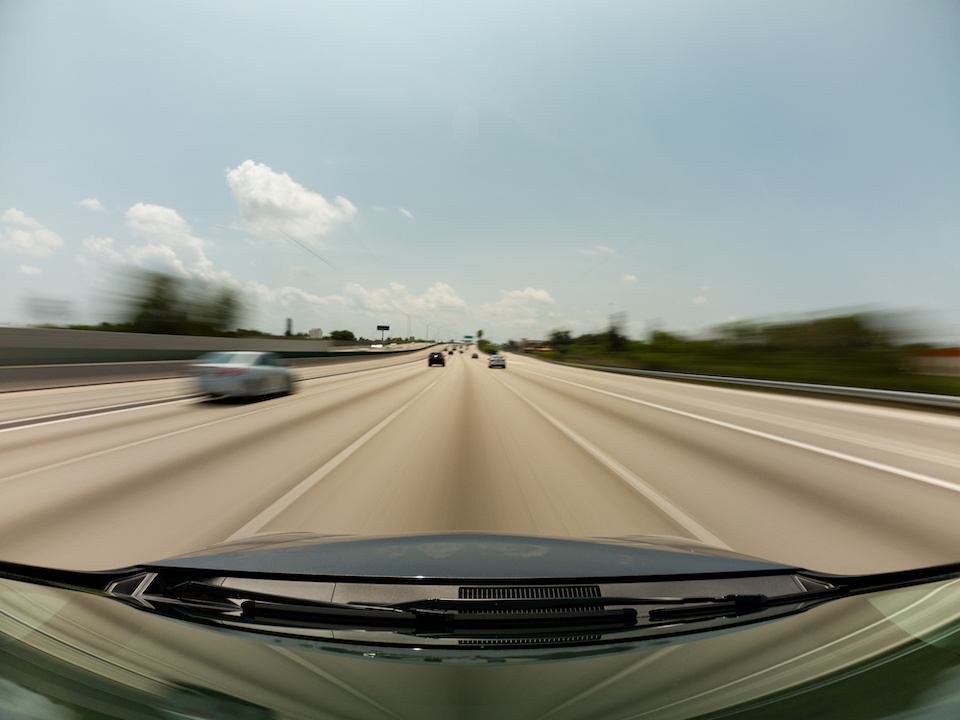 View through a front windshield of a car driving on a highway through the point of view of a dash cam. Depicts the strength of dash cam footage for strengthening a court case.